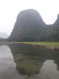 Scenic view of lake by mountain against sky