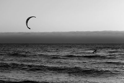 Mid distance view of person kiteboarding in sea against sky