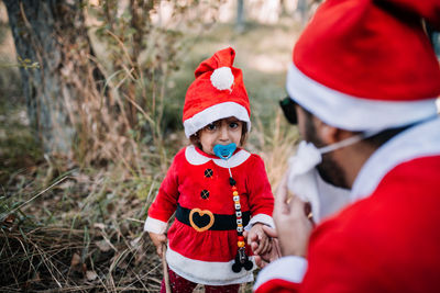 Portrait of cute baby girl wearing santa costume looking at father