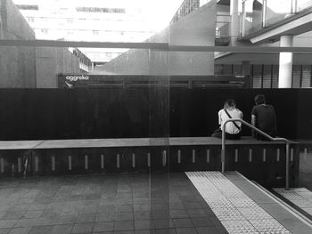 Rear view of couple sitting against the wall