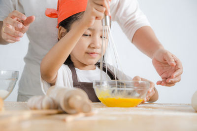 Man assisting girl preparing food at home