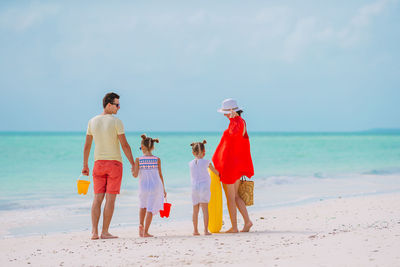 People on beach by sea against sky