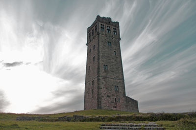 Low angle view of castle on field against cloudy sky