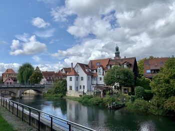 Houses by river and buildings against sky