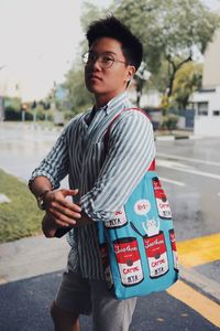 Young man looking away while standing on street in city