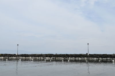 Wooden posts in sea against sky