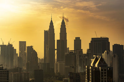 Petronas towers in city at sunset