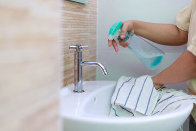 Cropped hand washing hands in bathroom