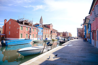 Boats moored in canal amidst buildings in city