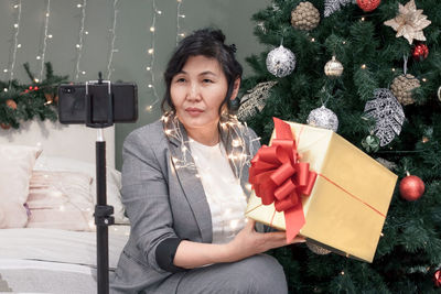 Portrait of young woman holding christmas tree