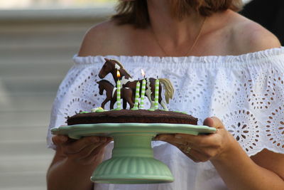 Midsection of woman holding birthday cake