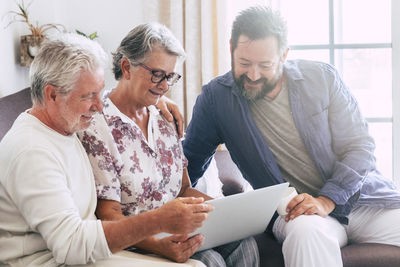 Family looking at laptop while sitting on sofa