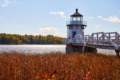 Lighthouse by sea against sky