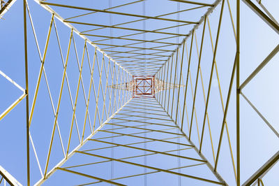 Electricity pylon in perspective seen from below with blue sky background