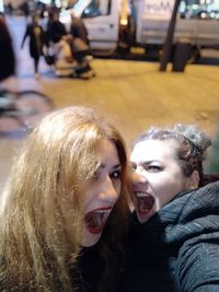 Portrait of cheerful friends in city at night