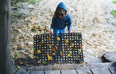 High angle view of boy holding doormat