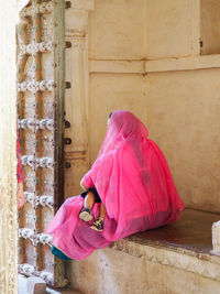 Woman with pink sari against wall of building