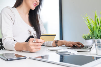 Midsection of woman using mobile phone while sitting on table