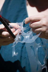 Midsection of woman cutting plastic with scissors