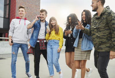 Friends using phones while standing on street