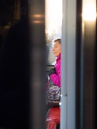 Young woman looking through window