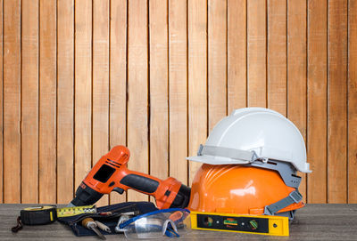 Construction tools on table against wooden wall