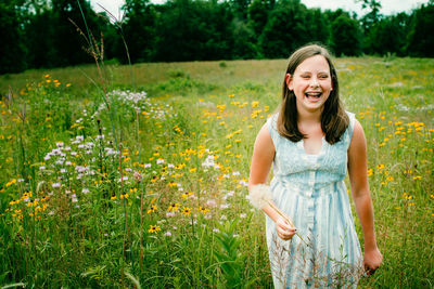 Portrait of smiling young woman standing in a wildflower field