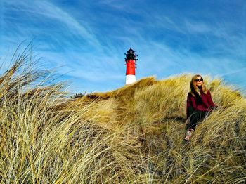 Man standing by lighthouse against sky