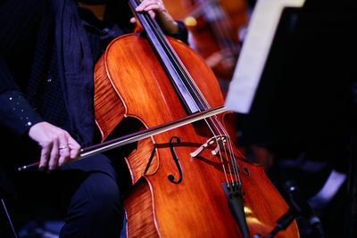 Midsection of musician playing cello on stage