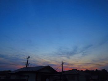 Low angle view of silhouette electricity pylon against sky