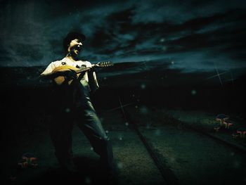 Man playing mandolin on street at night