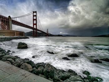 Bridge over sea against cloudy sky