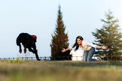 Woman playing with dog on field at park against sky