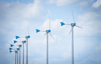 Low angle view of wind turbines against sky