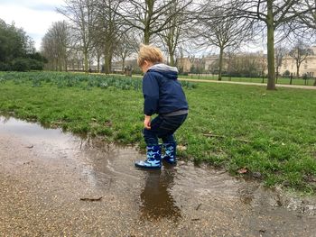 Boy jumping in puddle at park