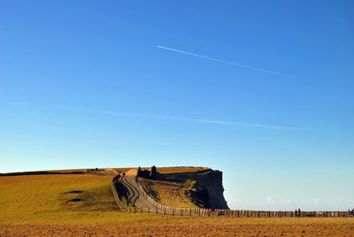 Footpath on hill against clear sky