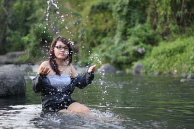 Portrait of young woman splashing water in lake