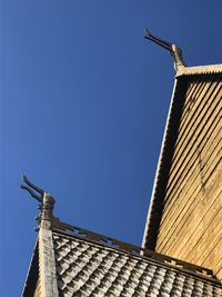 Low angle view of roof and building against clear blue sky