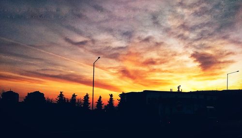 Silhouette trees and buildings against sky during sunset