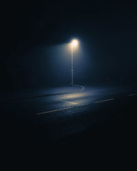 Illuminated street light on road at night