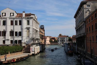 Canal amidst buildings in city against sky