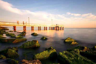 Pier over sea against sky during sunset