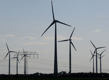 Low angle view of windmills on field against sky