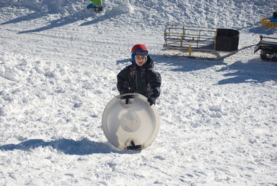 Boy with sled standing on snow