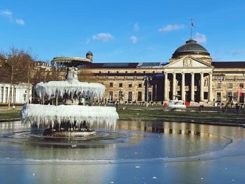 Fountain in front of building against sky