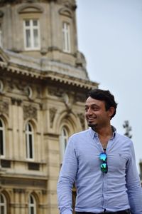 Smiling young man standing against built structure