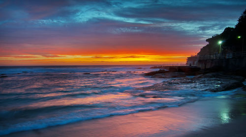 Scenic view of sea against cloudy sky during sunset