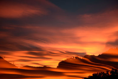 Scenic view of silhouette mountains against orange sky