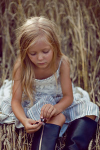 Blonde girl lying on the field among the dry ears of wheat in the summer