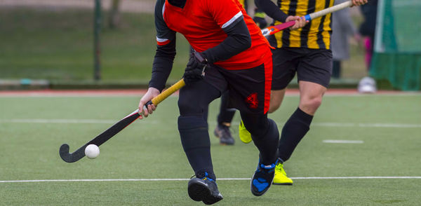 Low section of athletes playing of hockey on field